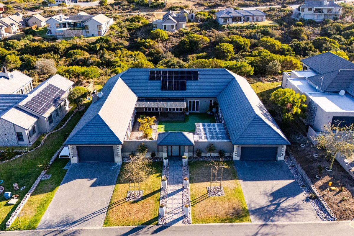 Aerial view of a modern U-shaped residential property featuring a central courtyard, dual garages, and solar panel installations on the roof.