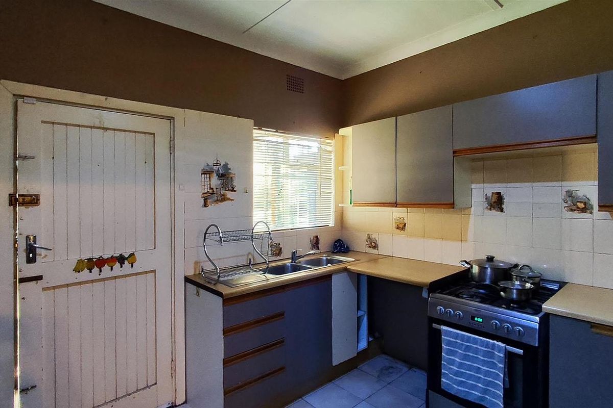 A functional kitchen featuring built-in cabinetry, a double sink, and a freestanding stove, offering a practical layout with potential for modernization.