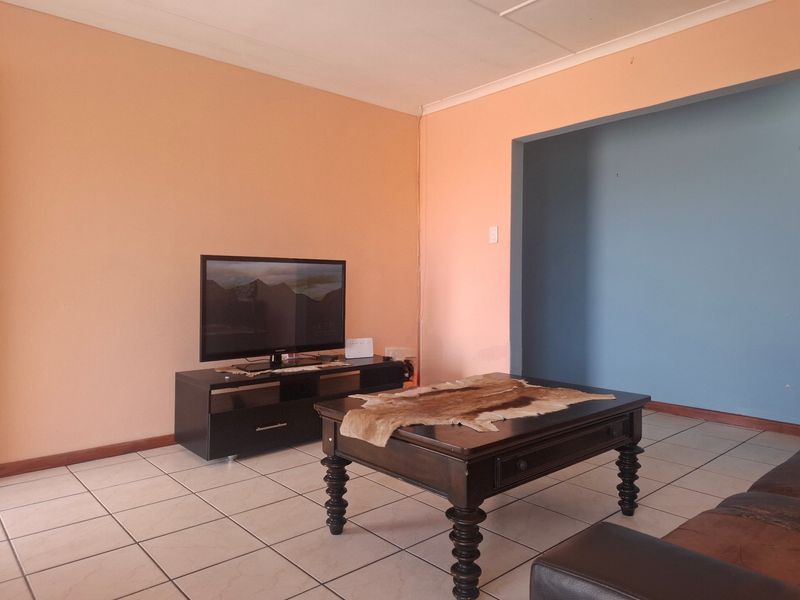 A living room area featuring tiled flooring and dual-tone painted walls, providing a functional space for relaxation.