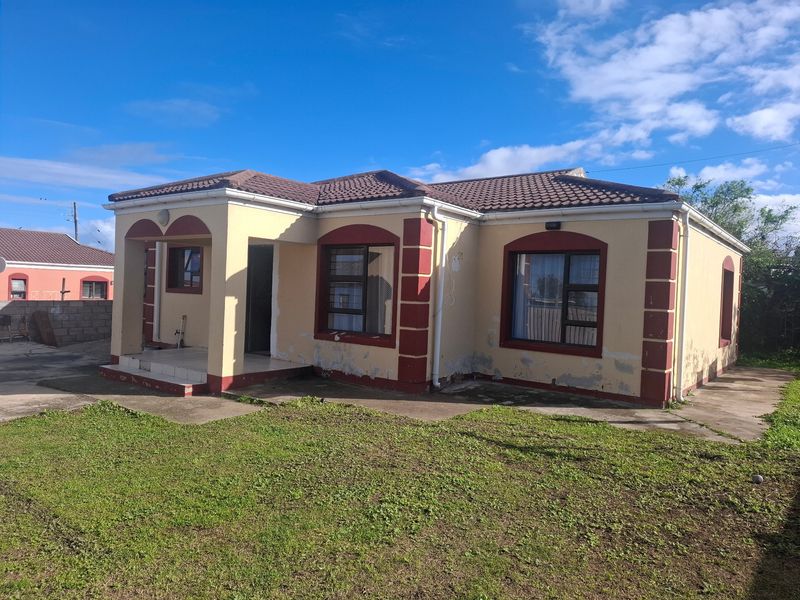 Front elevation of a single-story detached house featuring a tiled roof, covered entrance porch, and aluminium window frames, set on a grassed plot.