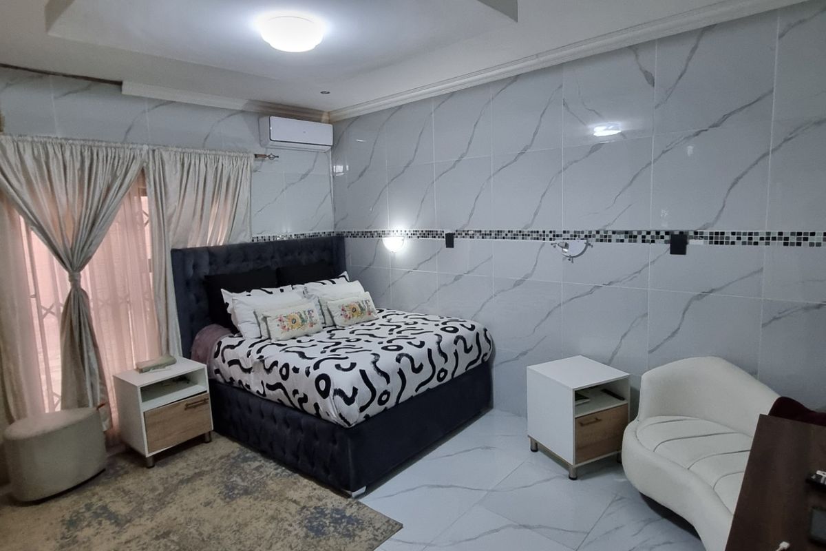 A bedroom featuring tiled walls and flooring, a wall-mounted air conditioning unit, and a sliding door with curtains.