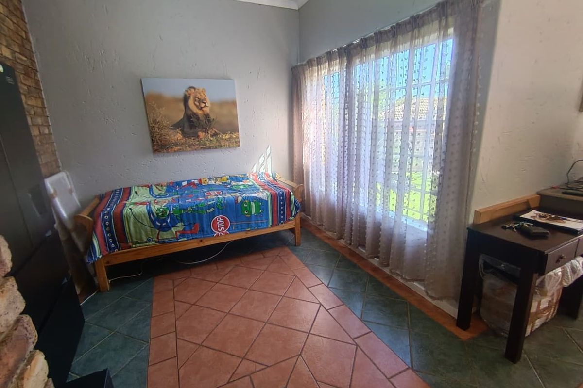 A bedroom featuring tiled flooring, a large window with curtains, and textured wall finishes.