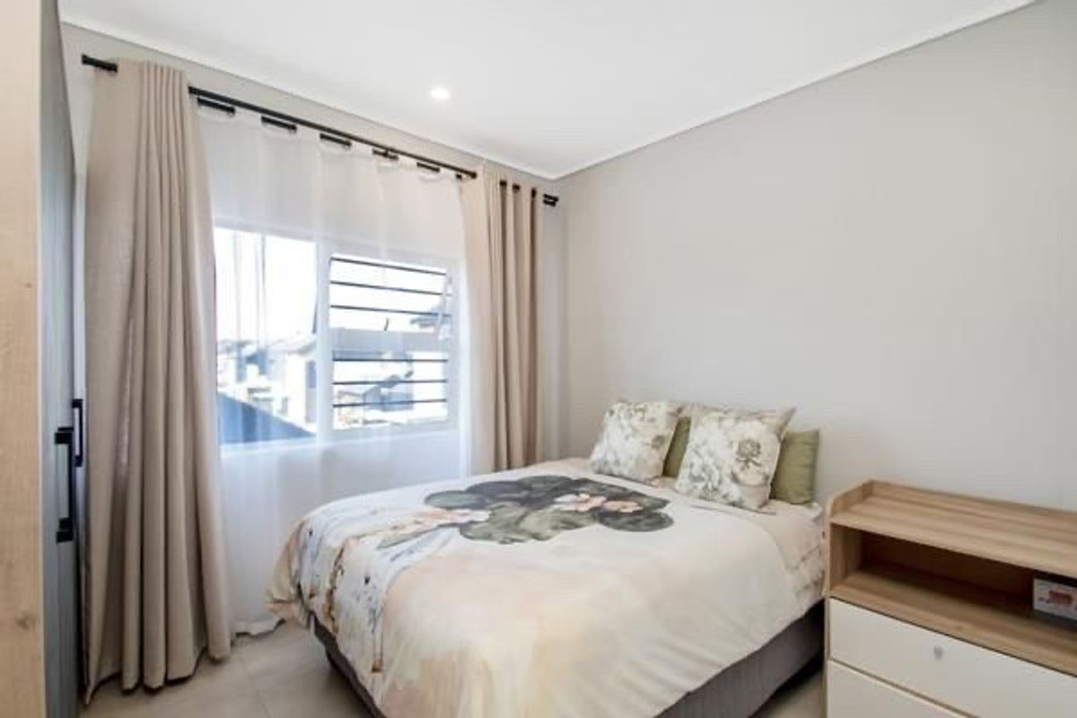 A well-maintained bedroom featuring neutral wall tones, large windows with curtain tracks, and recessed ceiling lighting.