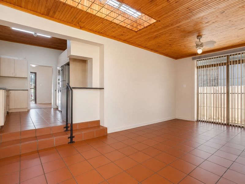 Open plan living area featuring terracotta floor tiles, a timber-clad ceiling with skylight, and direct access to an outdoor space.