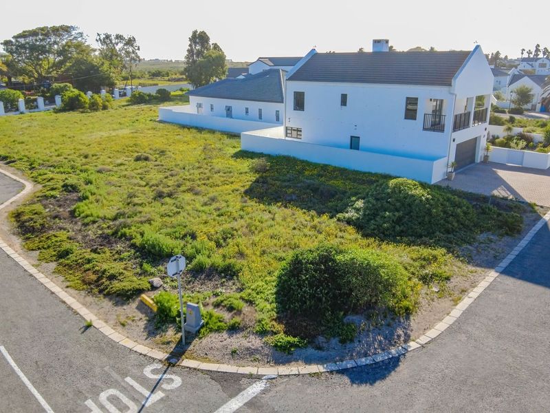 An elevated aerial view of a vacant residential corner plot situated in a developed neighborhood with established street infrastructure.