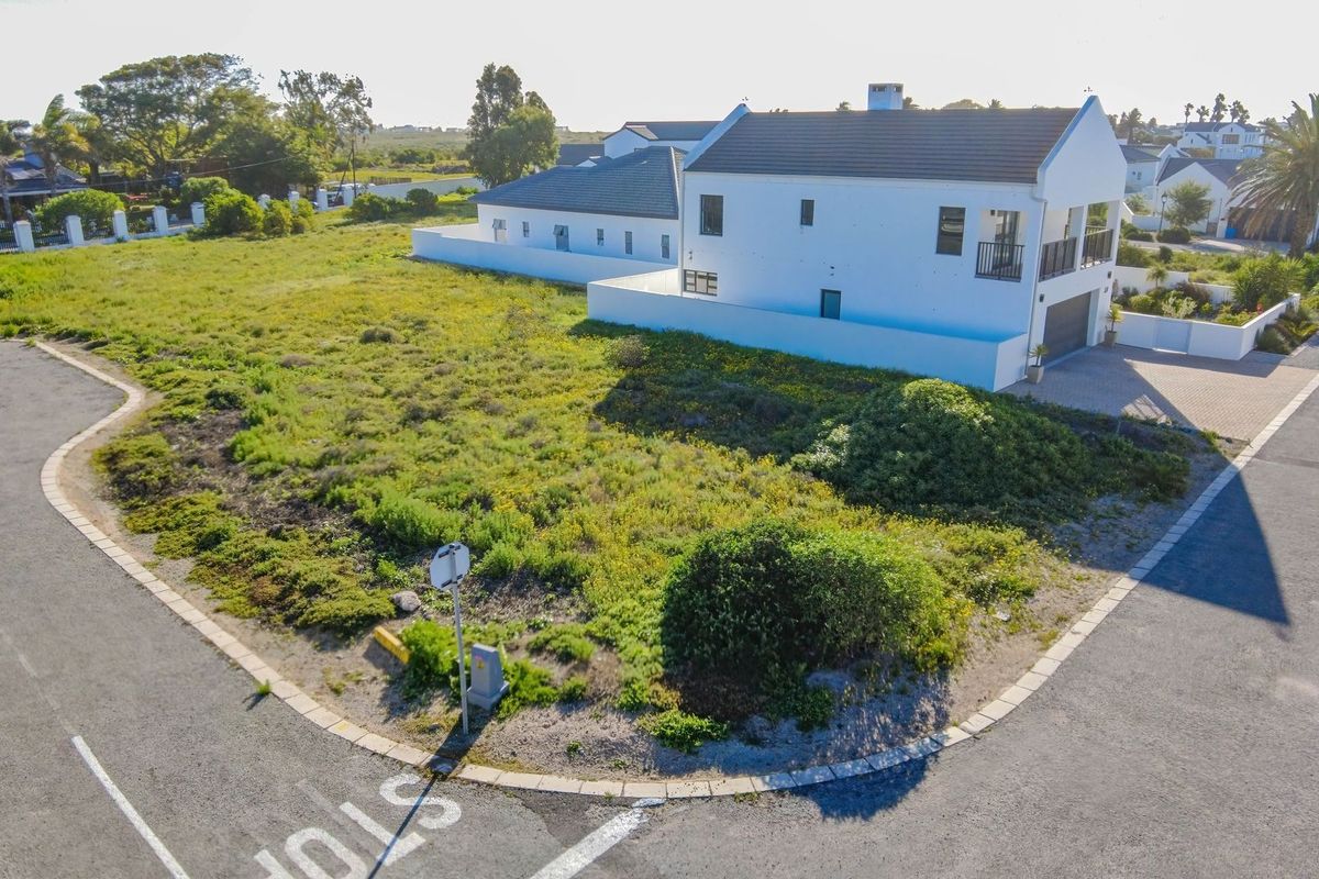 An elevated aerial view of a vacant residential corner plot situated in a developed neighborhood with established street infrastructure.