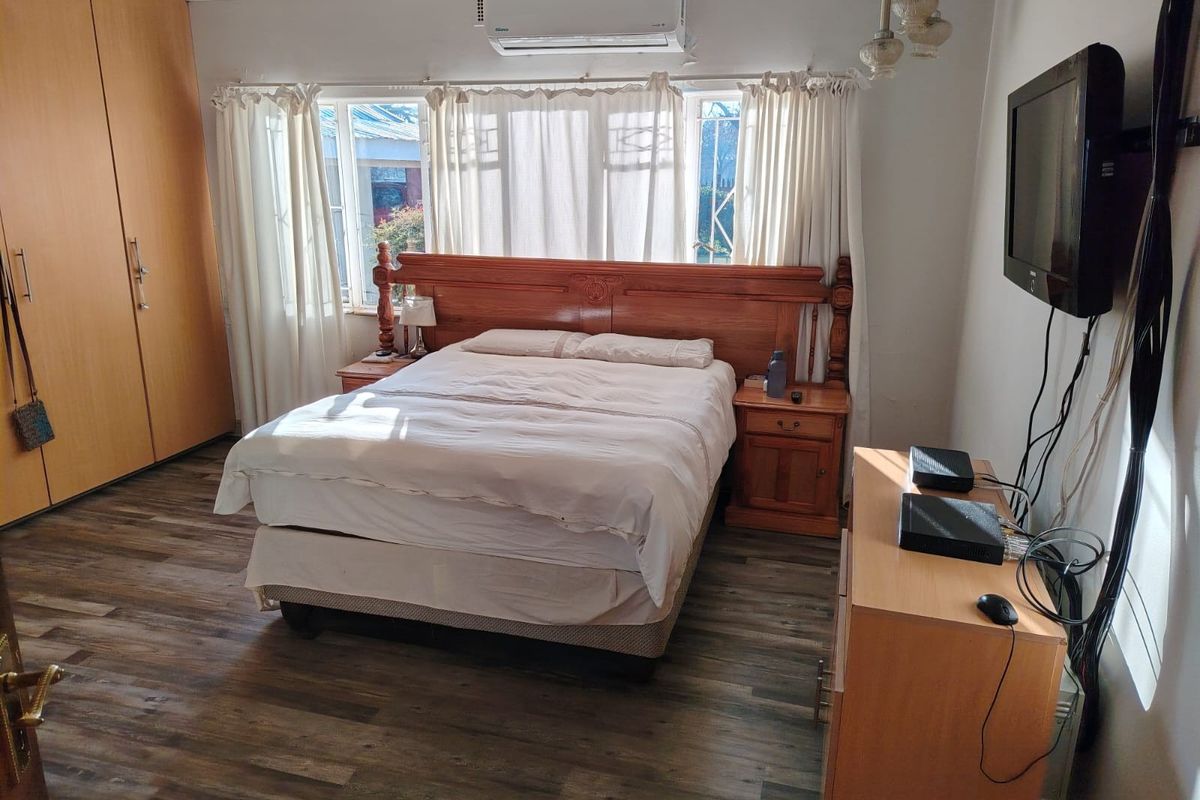 A bedroom featuring laminate flooring, a built-in wardrobe, and a wall-mounted air conditioning unit.