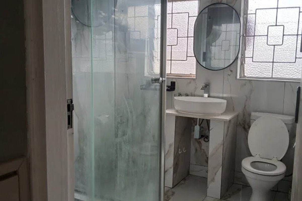 Modern bathroom featuring marble-look floor and wall tiles, a glass-enclosed shower, a vessel sink vanity, and a standard toilet.