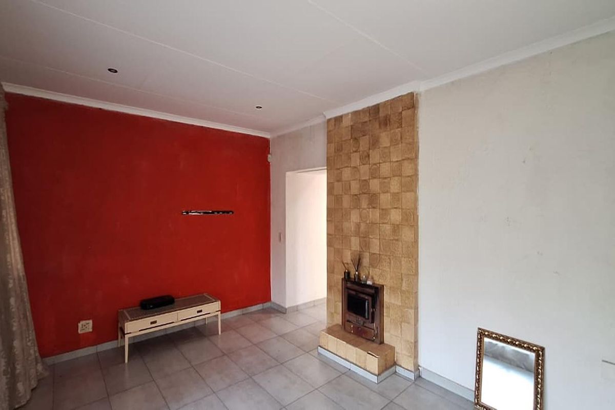 A living room featuring tiled flooring and a central fireplace with a textured stone-look surround.