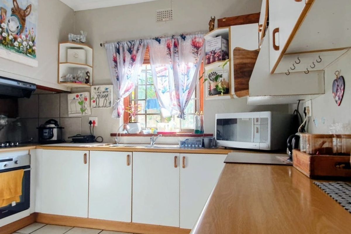 A functional kitchen featuring white cabinetry, wood-look countertops, a built-in oven, and a window overlooking the exterior.
