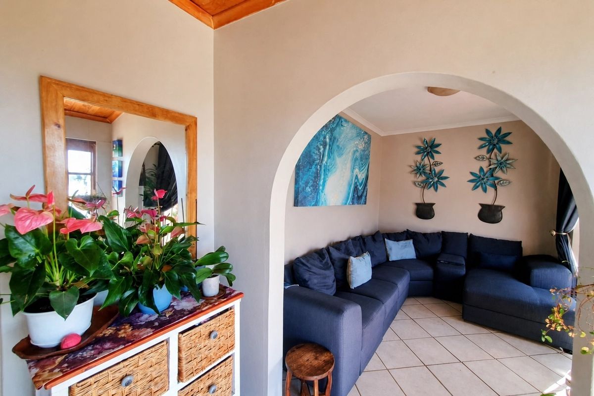 A cozy living room featuring a distinctive arched entryway, tiled flooring, and warm timber ceiling accents, creating a welcoming and comfortable atmosphere.