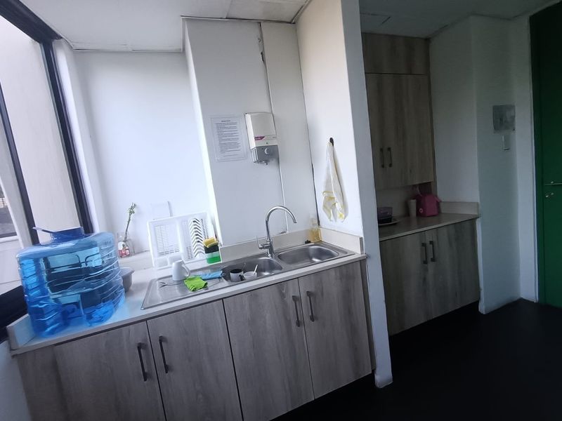 A functional office kitchenette featuring wood-grain cabinetry, a stainless steel double sink, and ample counter space for staff use.