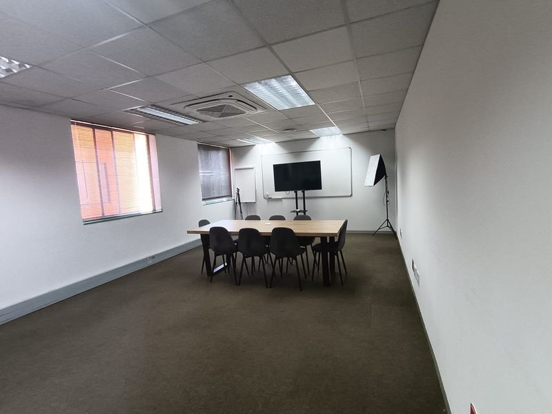 A functional office meeting room featuring a suspended ceiling, recessed lighting, integrated air conditioning, and carpeted flooring.