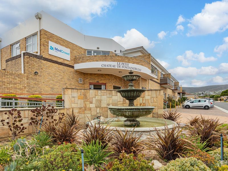 Front elevation of the retirement village featuring a brick facade, stone-clad retaining wall, and a central decorative water fountain.