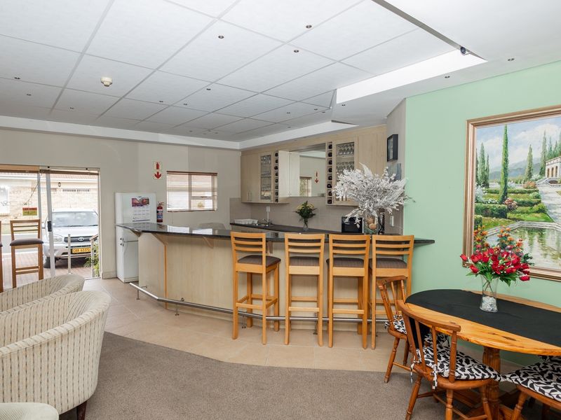 A well-maintained communal bar area featuring a built-in counter, bar seating, and direct access to the exterior through sliding glass doors.