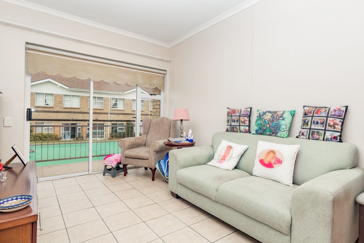 A living room featuring ceramic floor tiles and a large sliding glass door providing access to a balcony area.