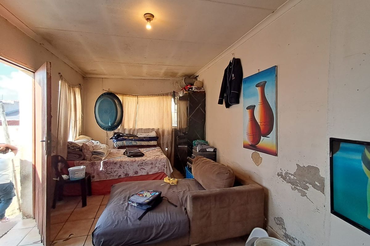A bedroom featuring tiled flooring and basic finishes, requiring cosmetic updates and wall repairs.