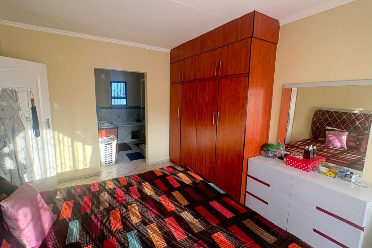 A bedroom featuring built-in wooden cabinetry and an en-suite bathroom with tiled flooring.