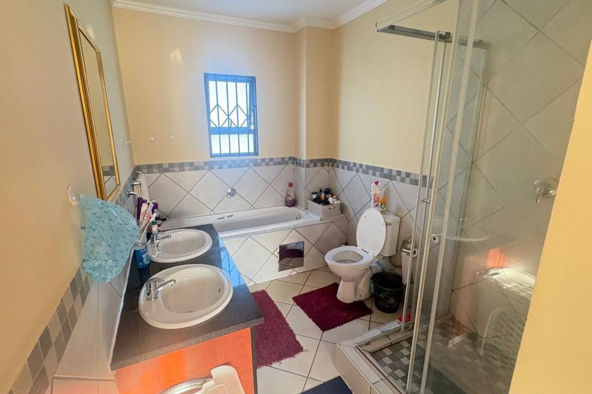 A functional bathroom featuring a double vanity with granite countertop, a built-in bathtub, a separate glass-enclosed shower, and a toilet.