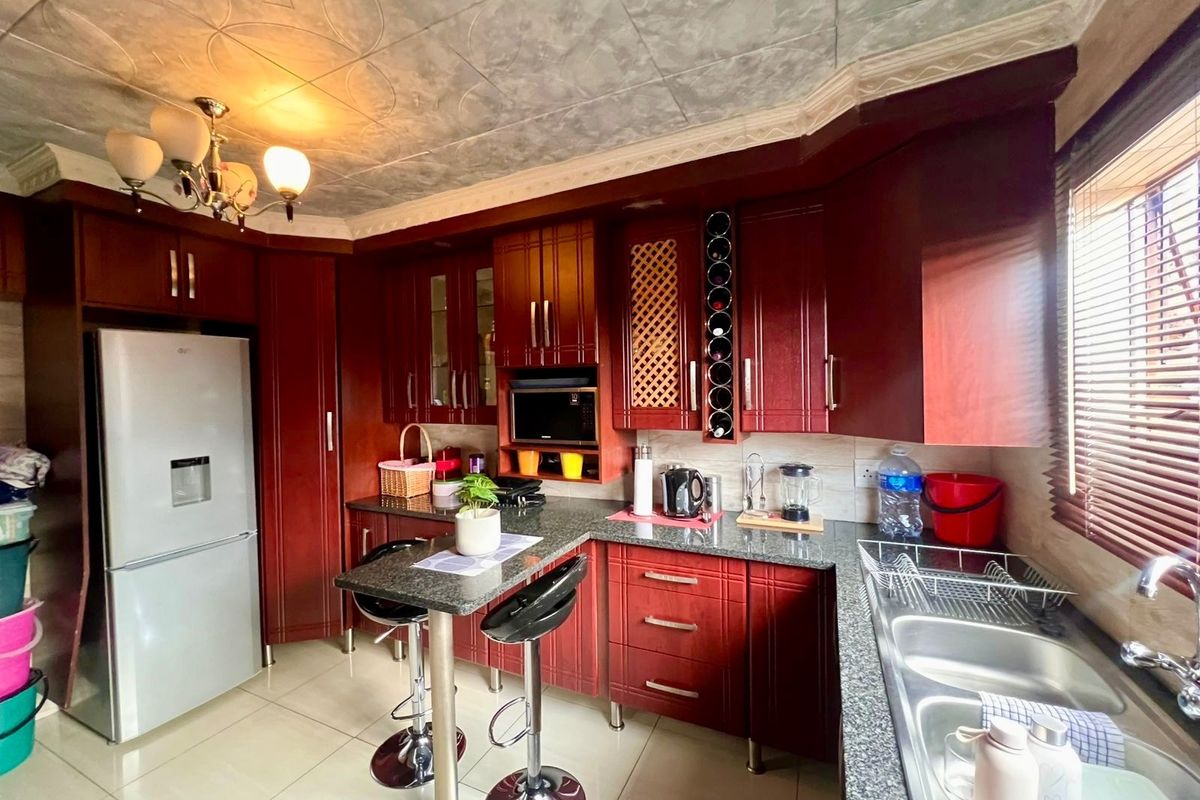 A functional kitchen featuring dark wood cabinetry, granite countertops, a double basin sink, and a built-in microwave with a breakfast nook area.