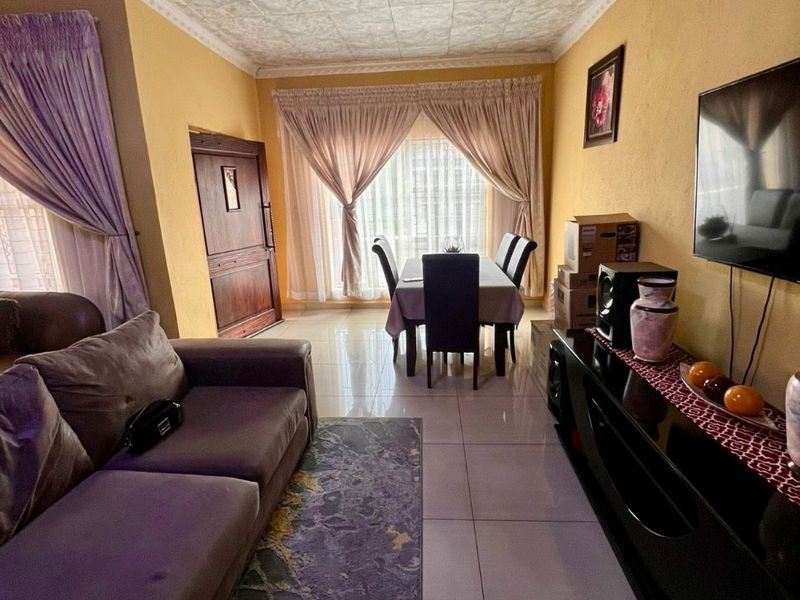 Open-plan living and dining area featuring large format floor tiles, textured ceiling panels, and decorative cornicing.