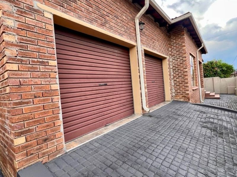 A double garage featuring face brick exterior walls and a paved driveway, providing secure off-street parking.