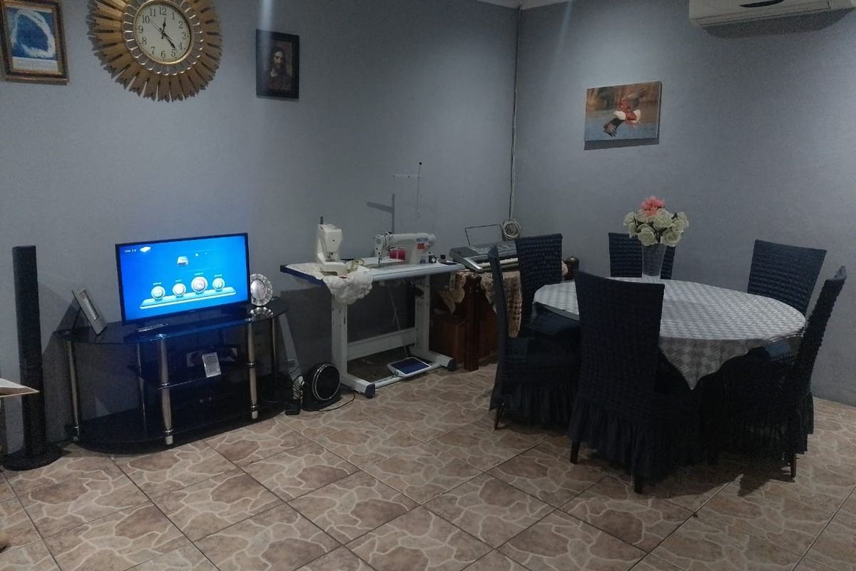A functional living and dining area featuring tiled flooring and a wall-mounted air conditioning unit.