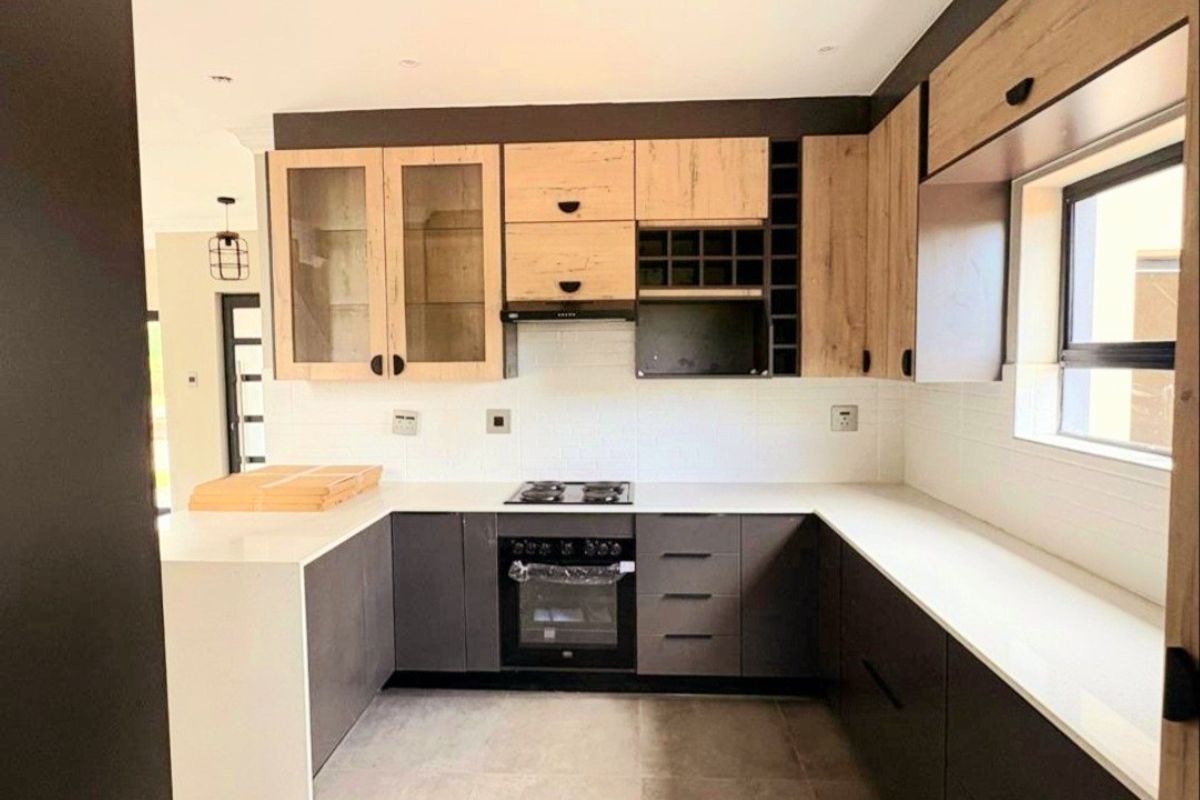 Modern U-shaped kitchen featuring two-tone cabinetry, stone countertops, integrated gas hob, oven, and extractor fan in a clean, contemporary finish.