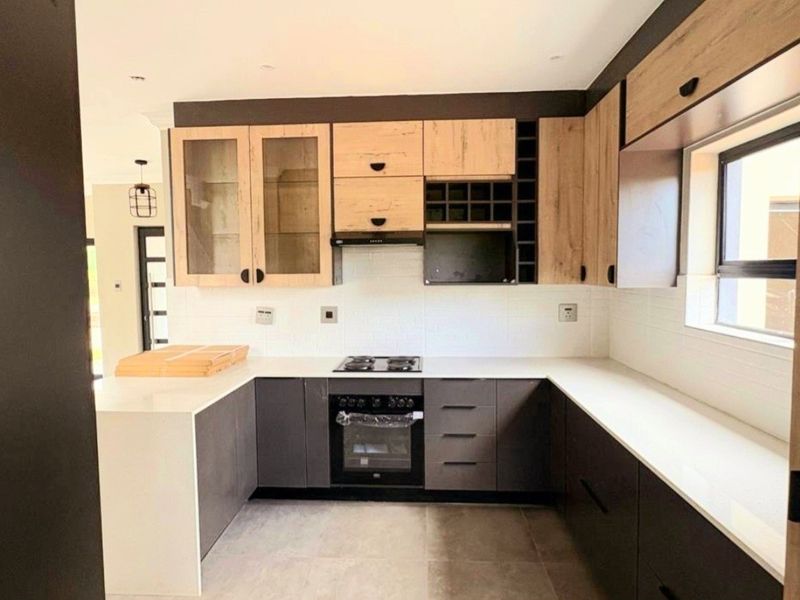 Modern U-shaped kitchen featuring two-tone cabinetry, stone countertops, integrated gas hob, oven, and extractor fan in a clean, contemporary finish.