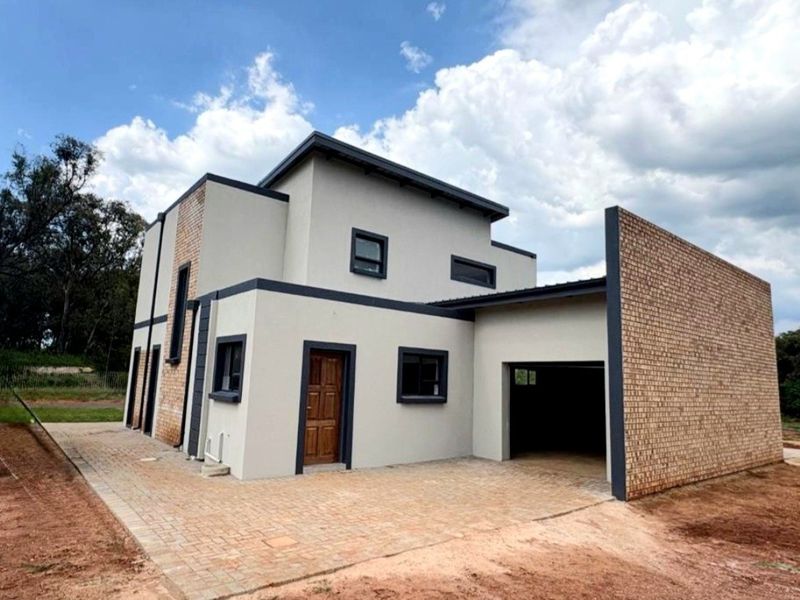 Modern double-storey house featuring a combination of rendered walls and face brick accents, with a paved driveway and integrated garage.