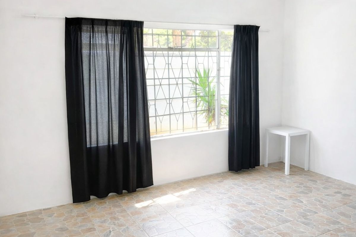 A bright, empty bedroom featuring tiled flooring, a window with security bars, and neutral white walls.