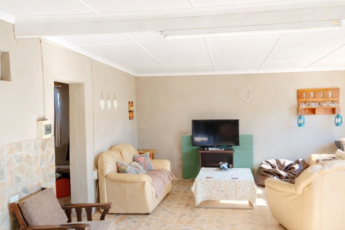 A living room featuring tiled flooring, a paneled ceiling, and neutral wall tones, providing a functional space for relaxation.