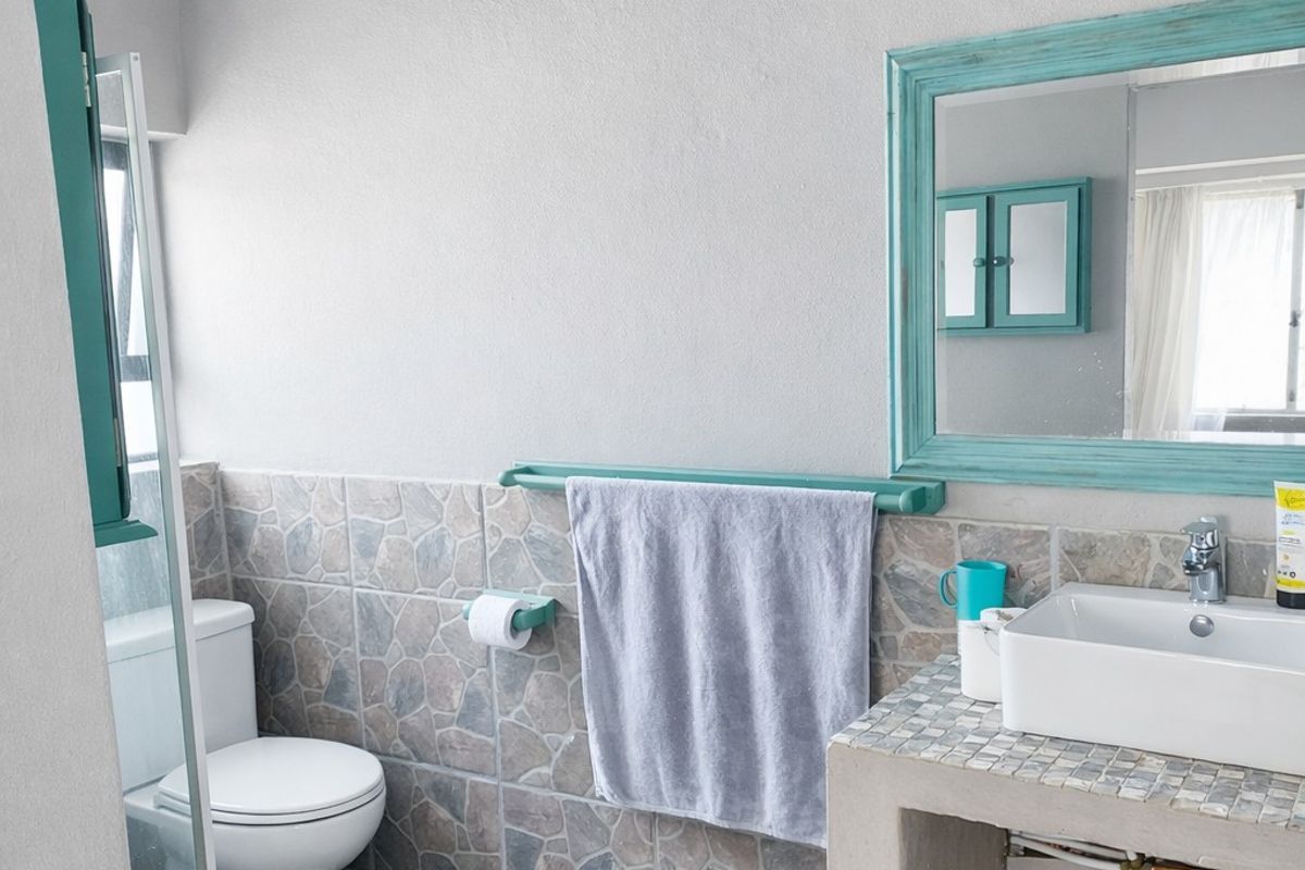 A functional bathroom featuring a vessel sink on a concrete vanity, a toilet, and decorative stone-look wall tiling.
