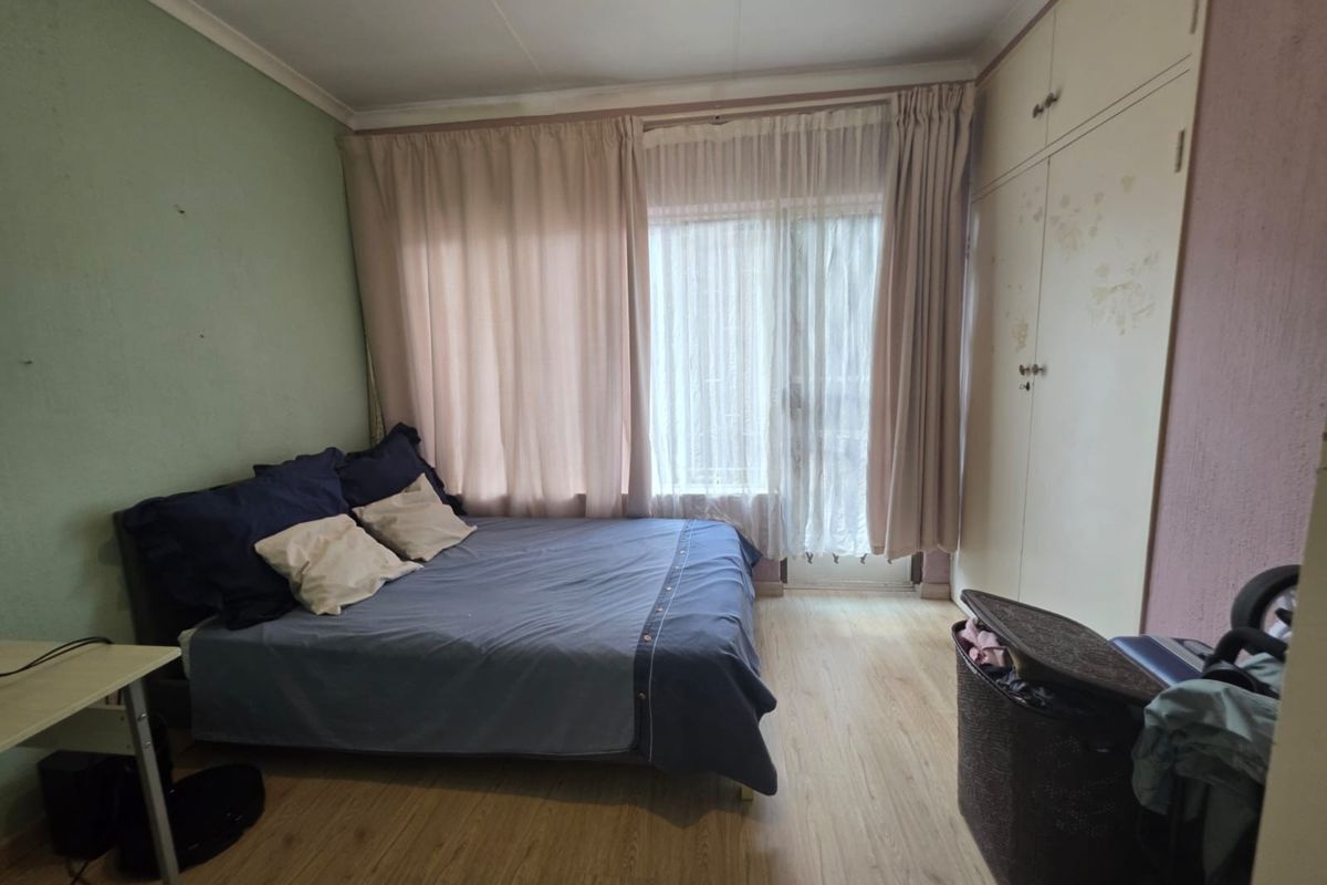 A bedroom featuring laminate flooring, built-in cupboards, and a sliding door providing access to the exterior.