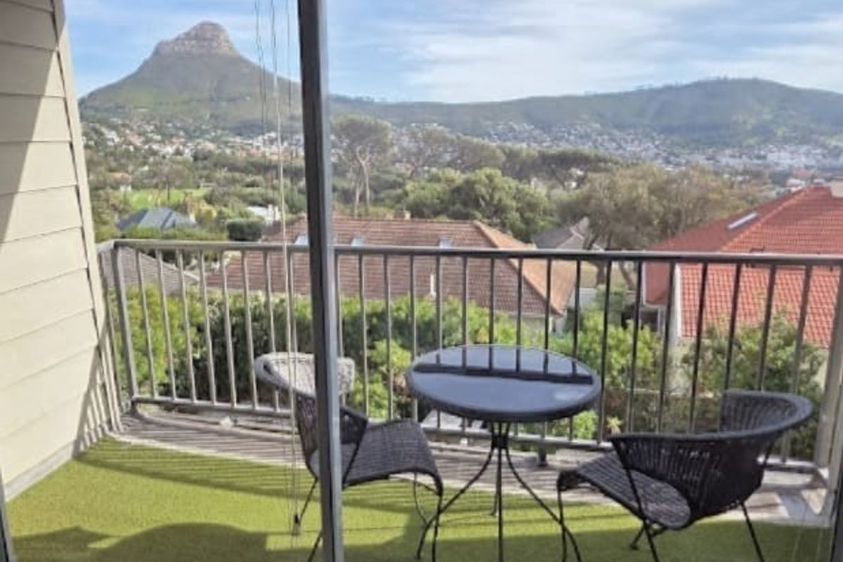 A balcony featuring a metal balustrade and artificial turf flooring, offering expansive mountain and suburban views.