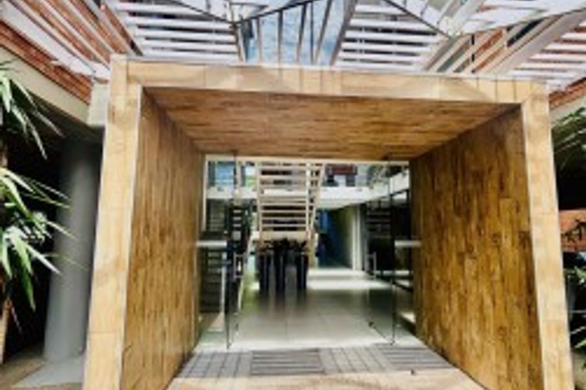 Modern office building entrance featuring a striking timber-clad walkway, glass doors, and a contemporary overhead architectural louvered canopy.