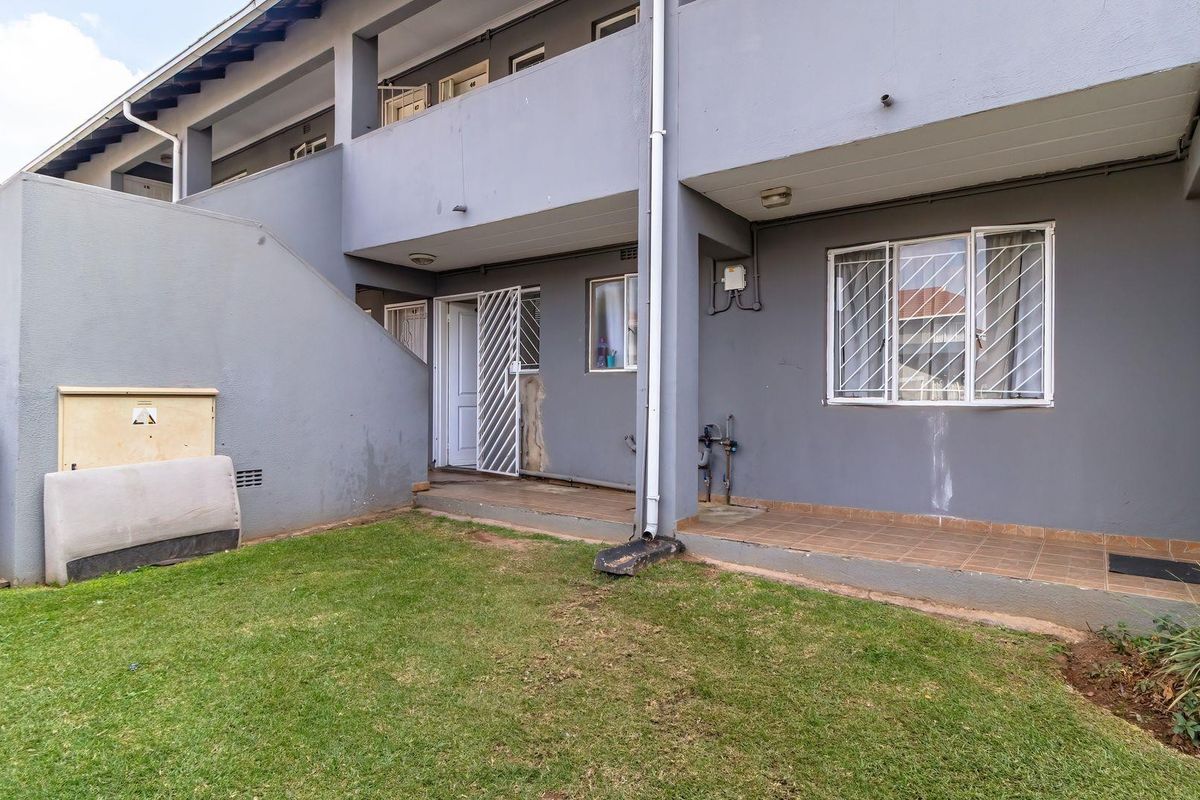 Rear view of the townhouse featuring a private patio area, small garden space, and access to the ground floor entrance.