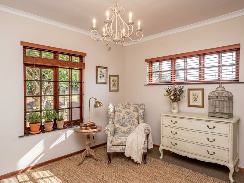 A well-maintained living area featuring classic wooden window frames, elegant coving, and a decorative chandelier, creating a warm and inviting atmosphere.