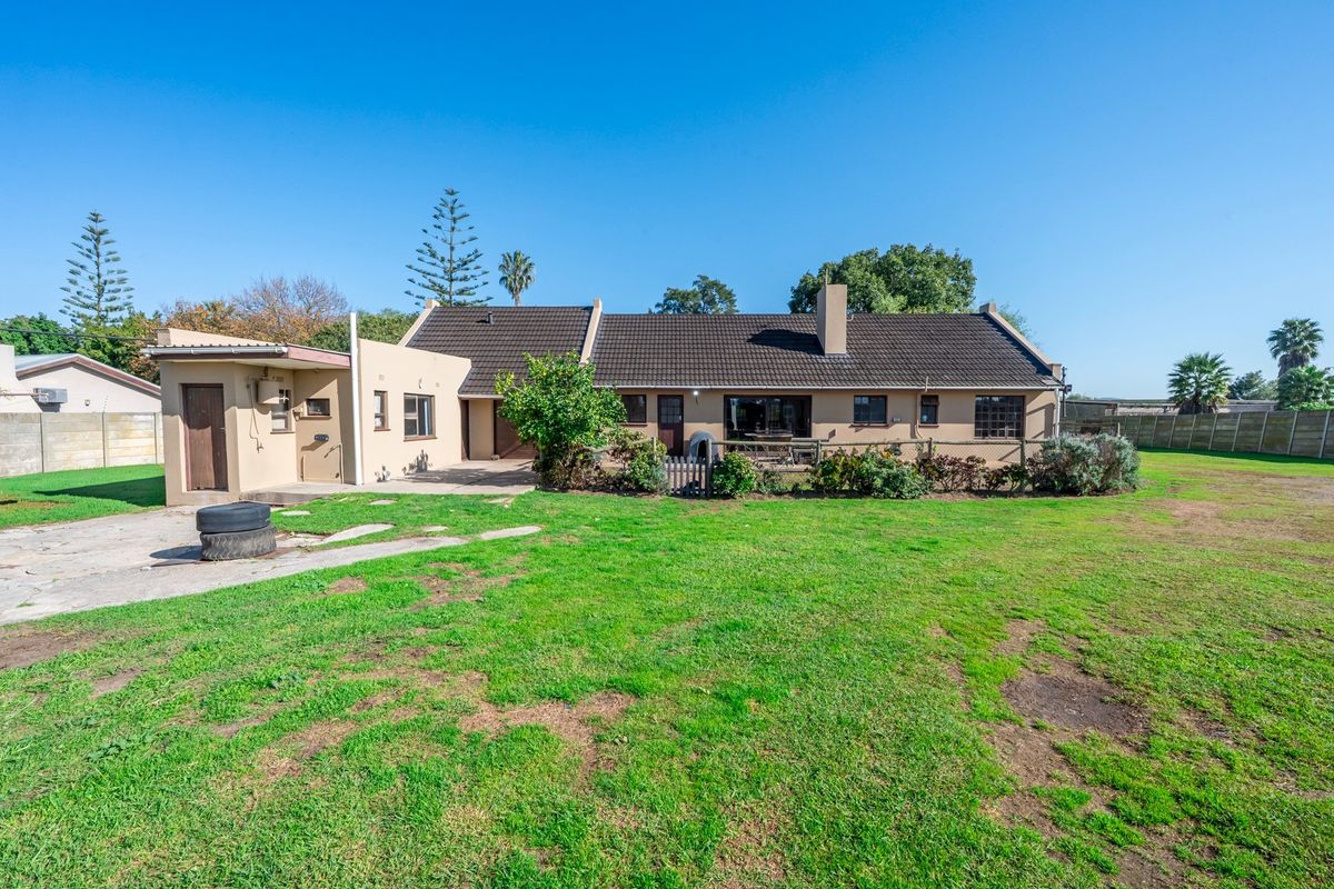 Rear view of the property featuring a tiled roof, chimney, and a spacious garden area with a concrete patio.