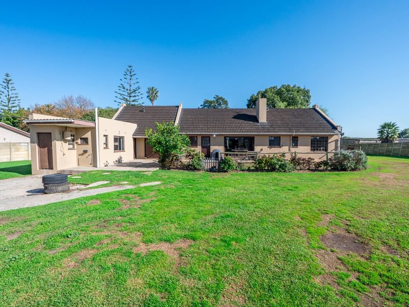 Rear view of the property featuring a tiled roof, chimney, and a spacious garden area with a concrete patio.
