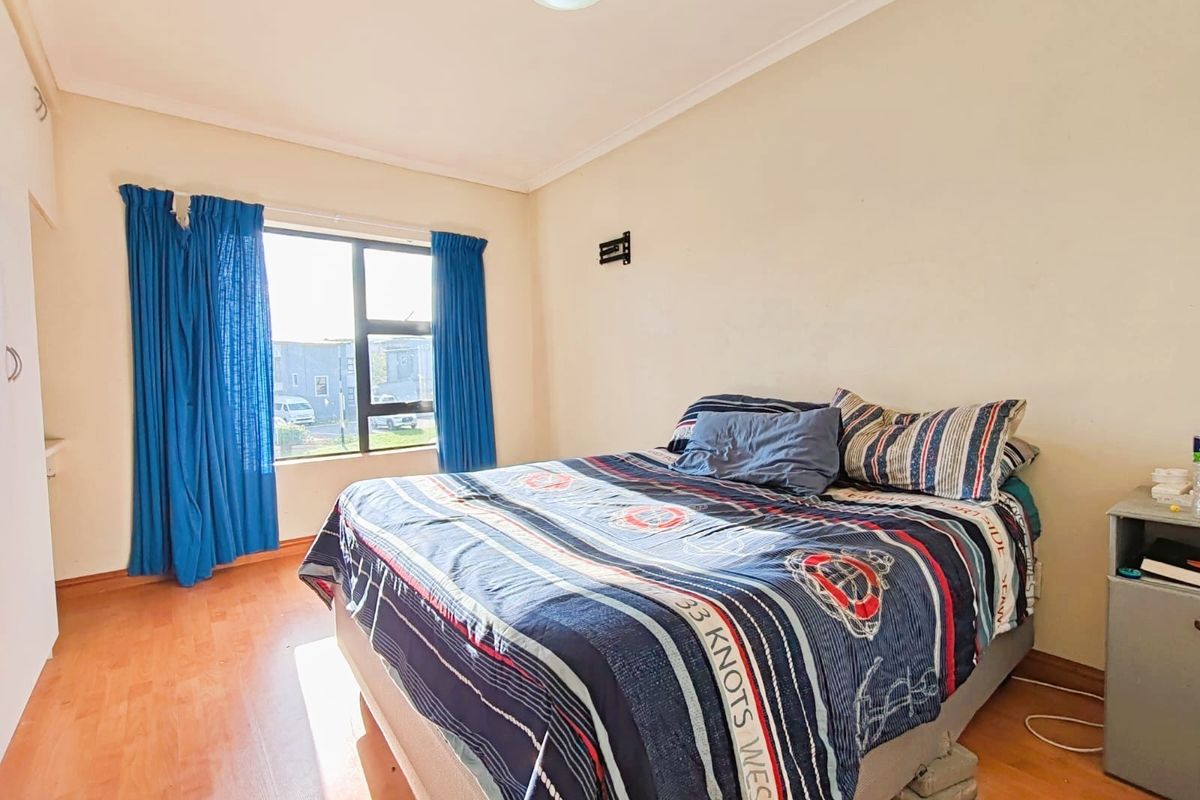 A bedroom featuring laminate flooring, a large window with natural light, and built-in cupboard space.