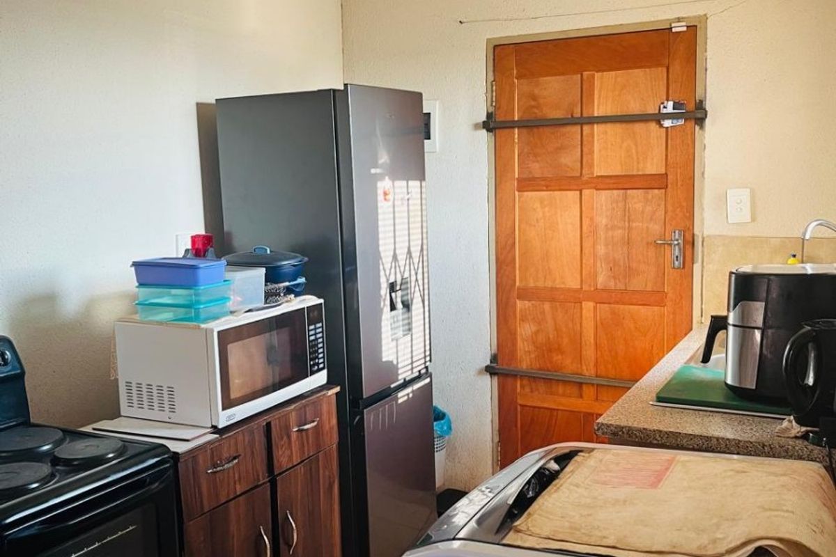 A functional kitchen area featuring dark wood cabinetry, a freestanding stove, and a rear exit door with security bars.