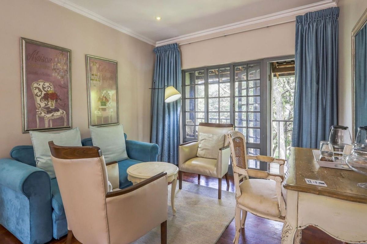 A cozy living area featuring hardwood flooring, crown molding, and French doors that open onto a private balcony.