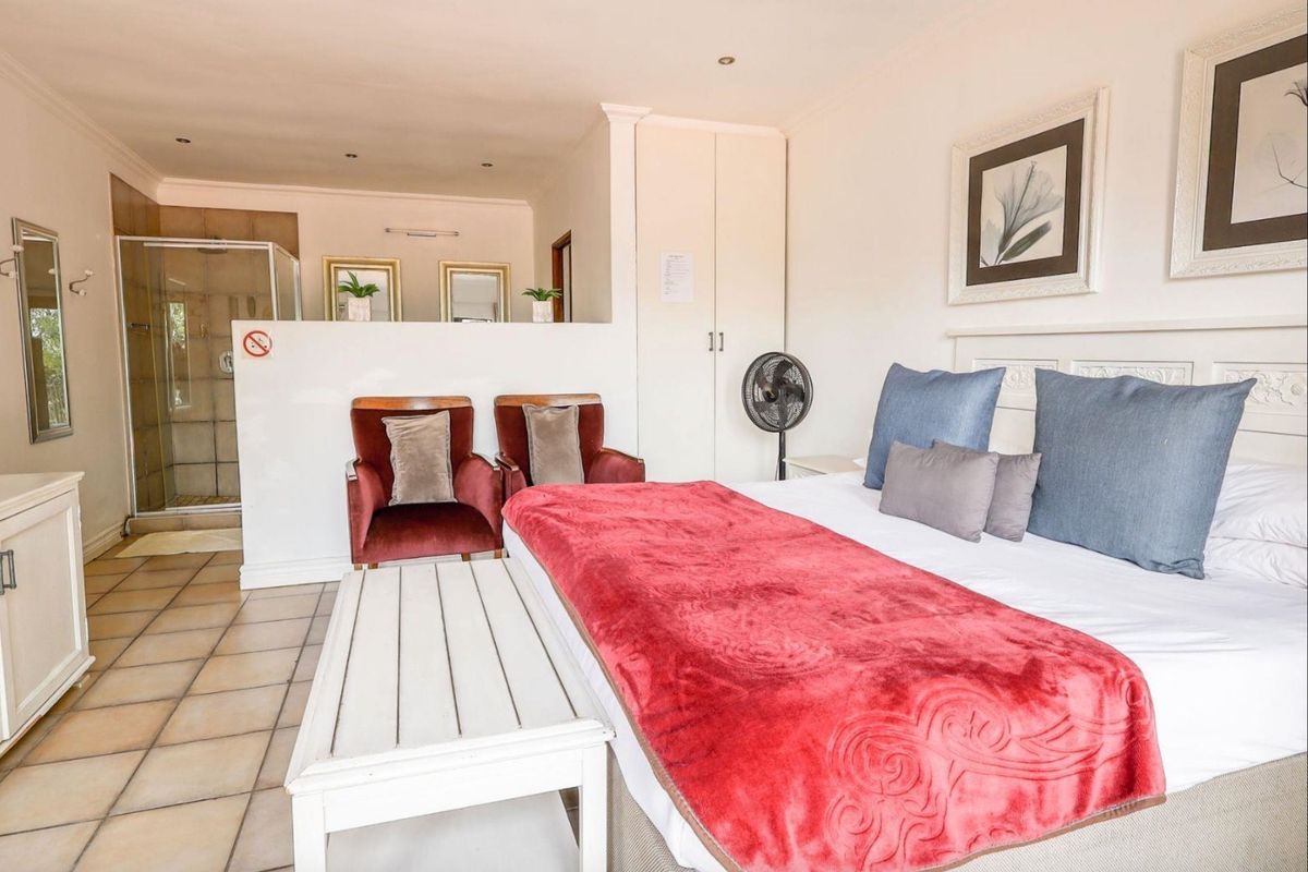 A spacious bedroom featuring an open-plan en-suite bathroom with a glass-enclosed shower and built-in cabinetry.