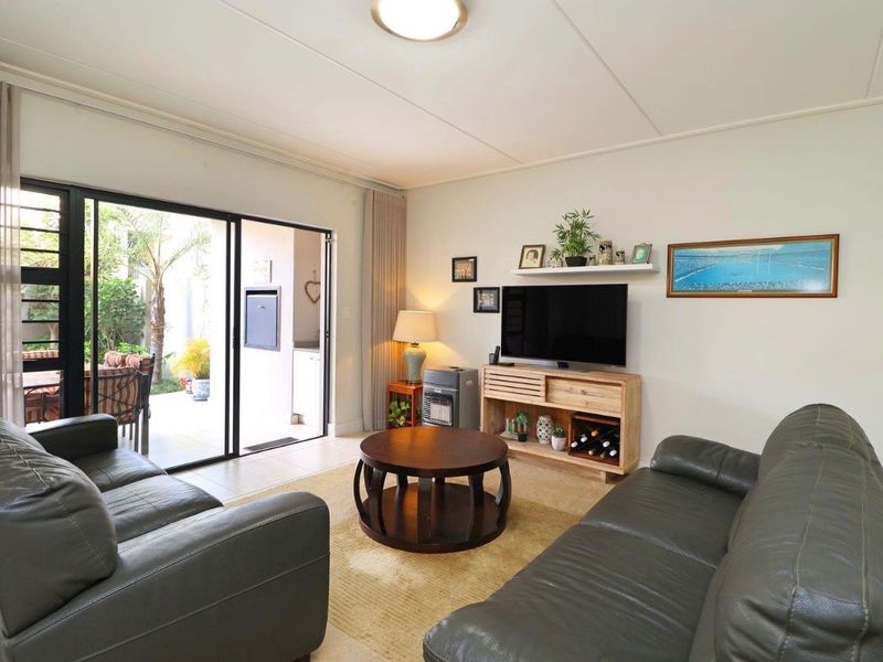 A well-maintained living room featuring tiled flooring and large sliding glass doors that provide direct access to an outdoor patio area.