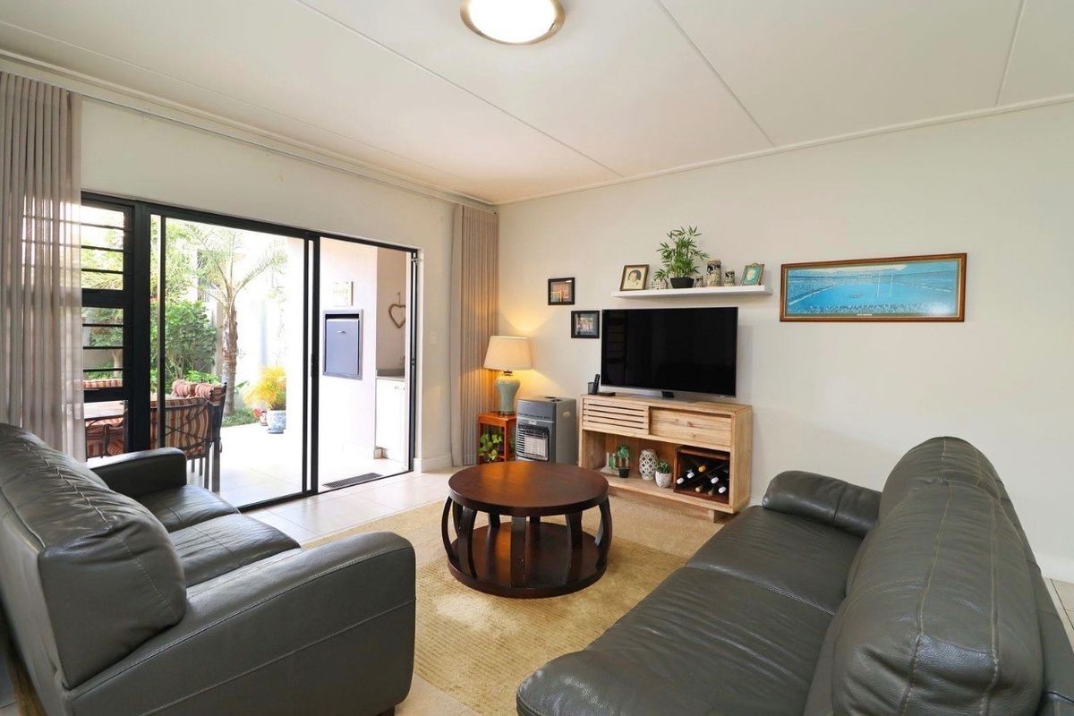 A well-maintained living room featuring tiled flooring and large sliding glass doors that provide direct access to an outdoor patio area.