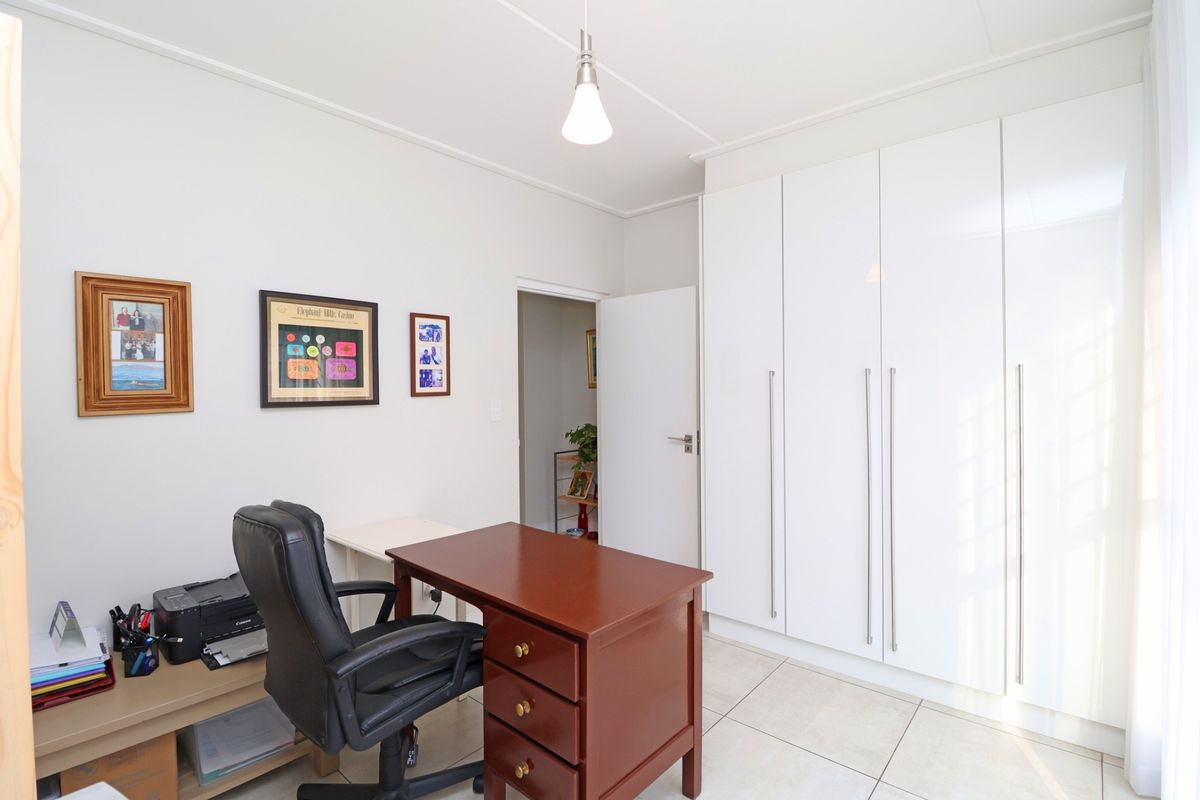 A well-maintained bedroom featuring neutral tiled flooring and ample built-in cupboard storage with modern white finishes.
