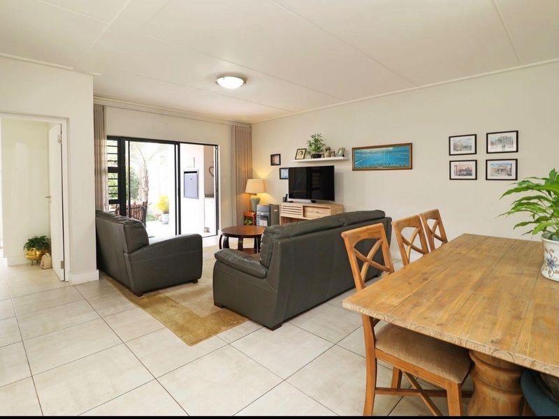 Spacious open-plan living and dining area featuring neutral tiled flooring and large sliding glass doors providing access to the outdoor patio.