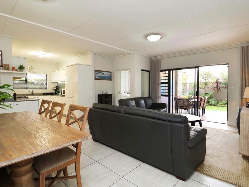 Spacious open-plan living and dining area featuring tiled floors, a modern kitchen, and seamless access to a private outdoor patio through sliding glass doors.