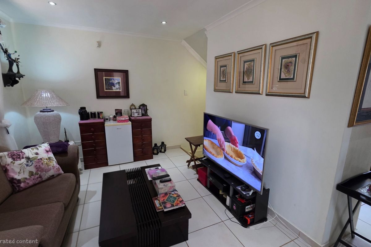 A living room area featuring tiled flooring, recessed ceiling lighting, and a neutral wall finish, providing a functional and comfortable space.